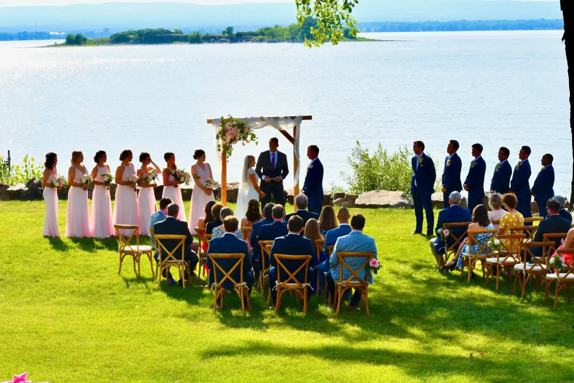 An elegant wedding ceremony on a lush lawn, with a picturesque lake in the background.