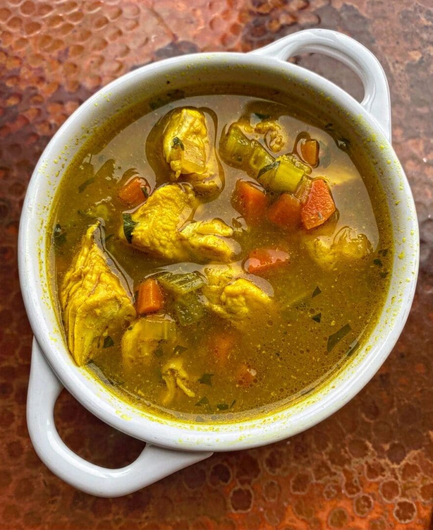 A bowl of Chicken Turmeric Lemongrass stew on a table.