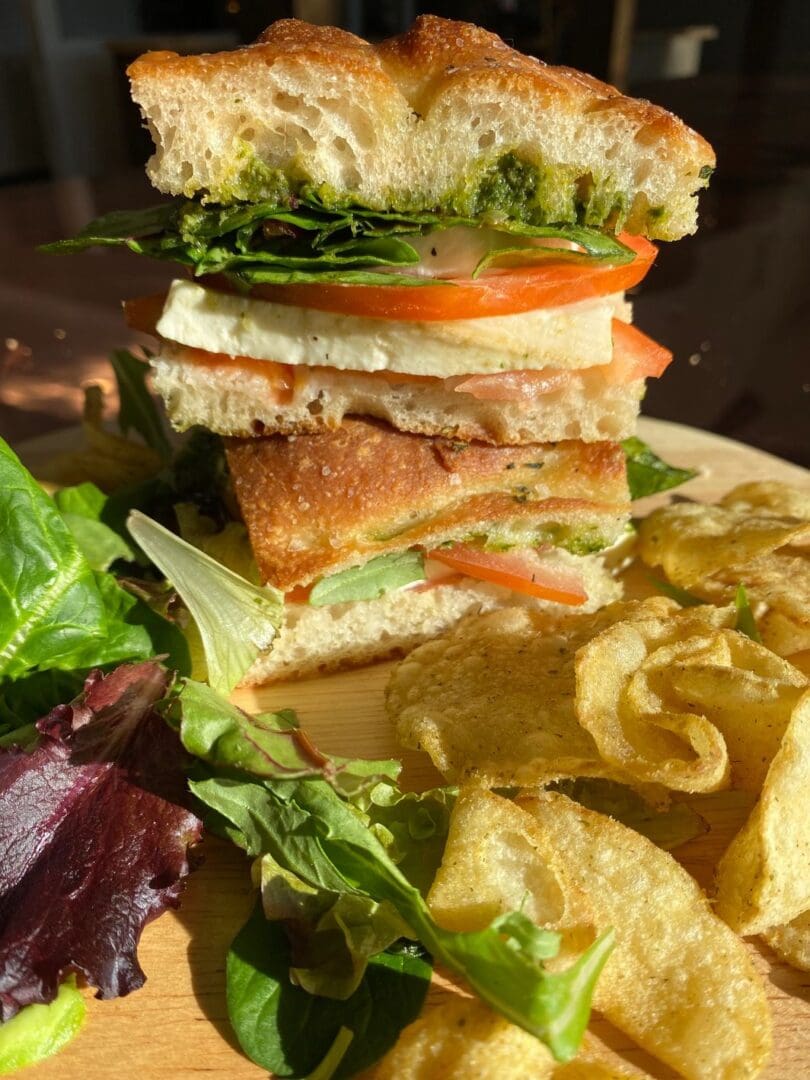 A Caprese on Focaccia on a plate with chips and salad.