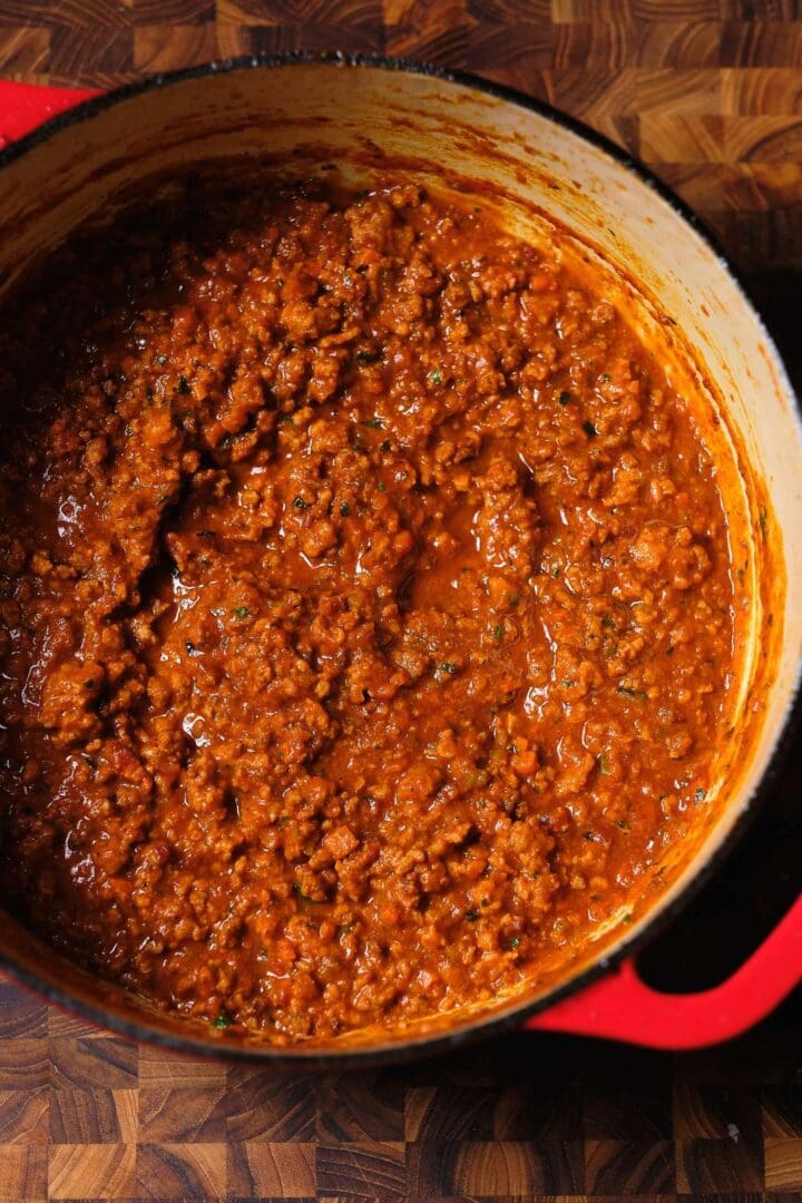 Bolognese Frozen Quart in a red pot on a wooden table.