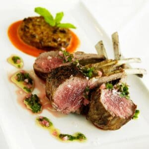 Rack of Lamb on a white plate with sauce.