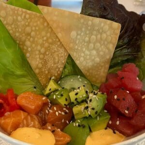 A Poke Bowl filled with a variety of sushi and vegetables.