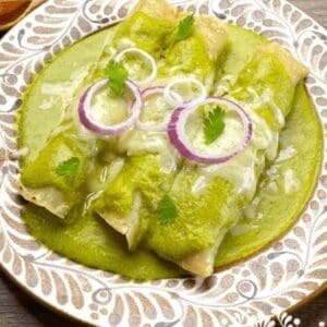 Enchiladas Verdes- Frozen with green sauce on a plate.