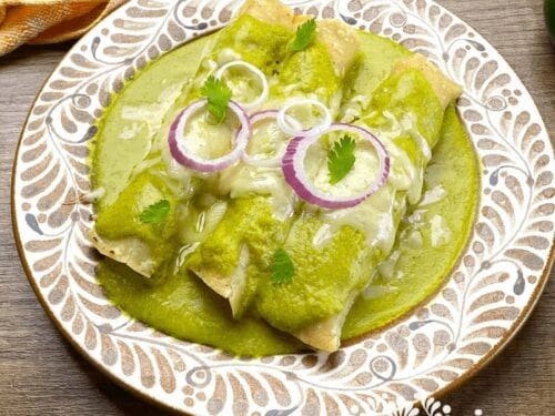 Enchiladas Verdes- Frozen with green sauce on a plate.