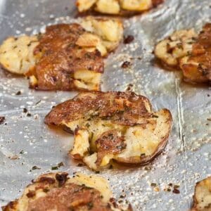 A tray of Roasted Red Bliss Smashed Garlic Potatoes on a baking sheet.