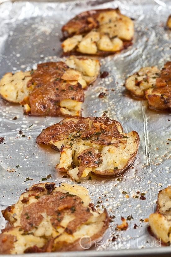 A tray of Roasted Red Bliss Smashed Garlic Potatoes on a baking sheet.