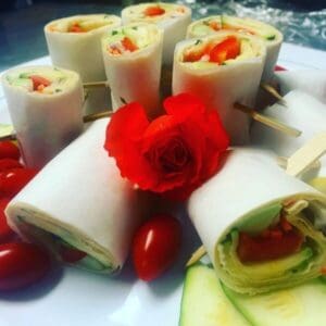 A plate of Vegetarian Wraps with tomatoes and cucumbers on it.