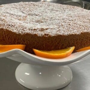 A Moroccan Meskouta Cake with orange slices and powdered sugar.