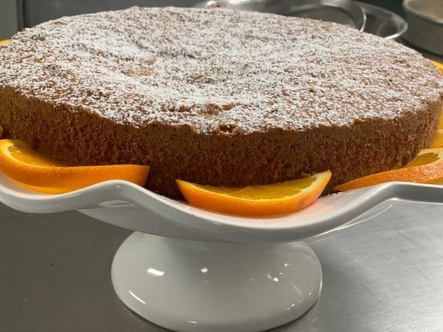 A Moroccan Meskouta Cake with orange slices and powdered sugar.