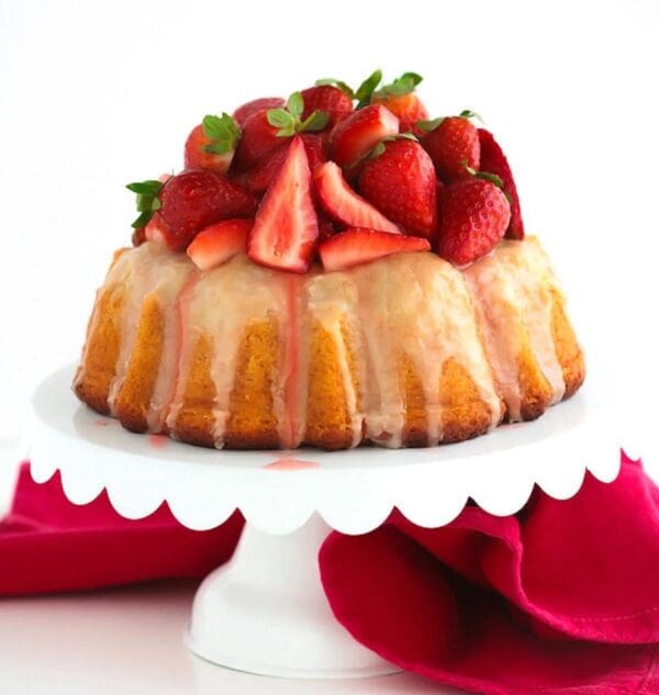 A Vanilla Bean Bundt Cake with Fresh Strawberries topped with icing.