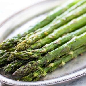 Asparagus with Herb Butter spears on a silver plate.